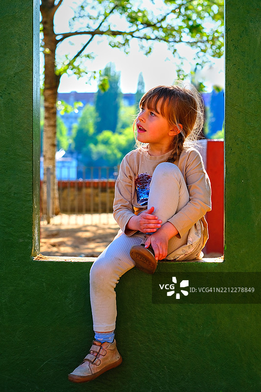 坐在绿色框架中的小女孩 - 深思的户外时刻图片素材