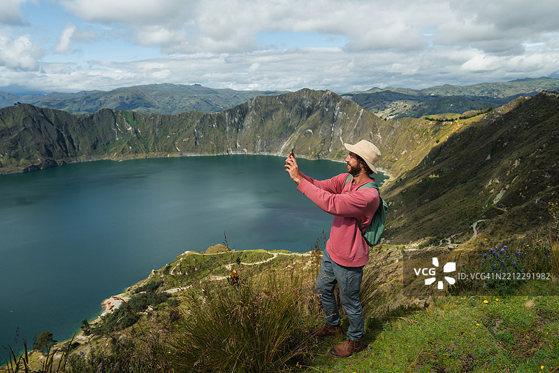 在厄瓜多尔基洛托阿湖火山口附近徒步旅行时用智能手机拍照的男子图片素材