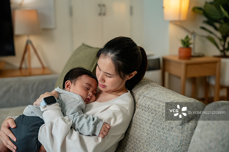 快乐的亚洲母亲抱着她的儿子。父母在家支持小男孩。图片素材