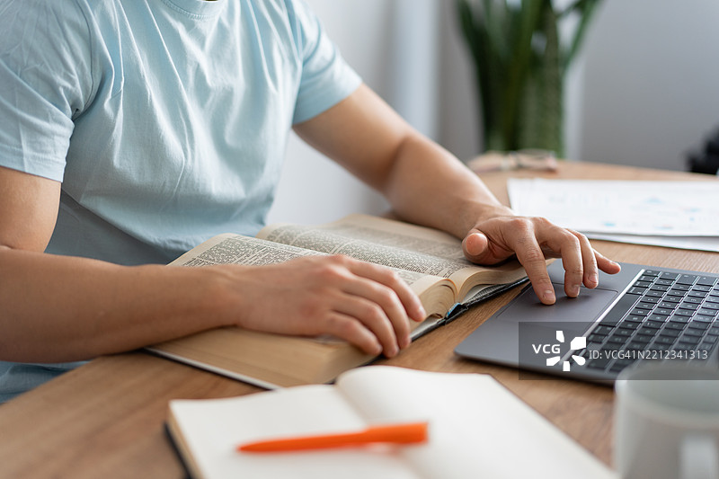 学生在家阅读书籍并使用笔记本电脑工作图片素材