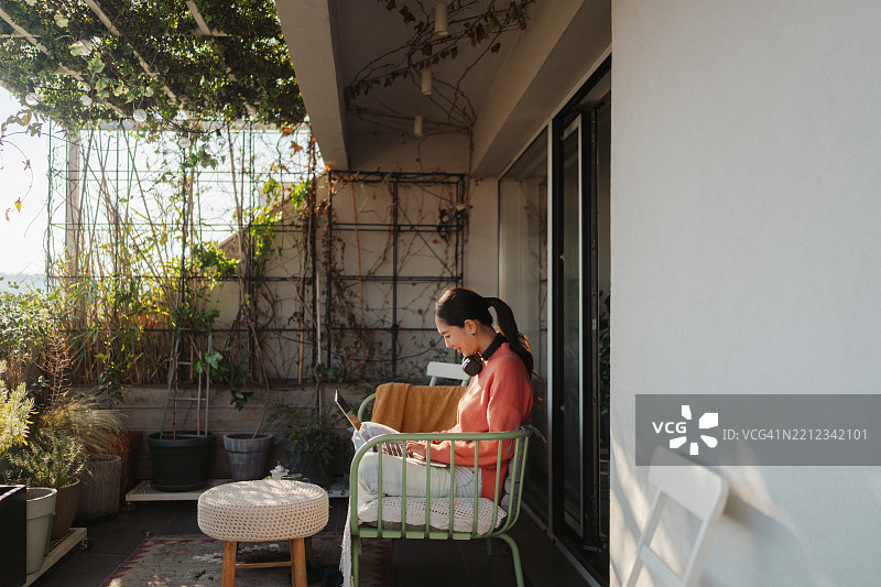日本女性在她的阁楼公寓阳台上使用笔记本电脑图片素材