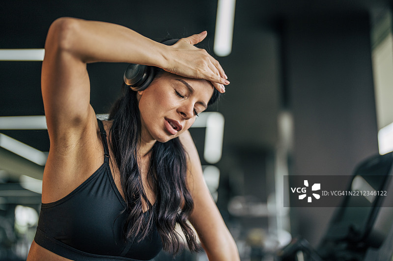 疲惫的女运动员在健身房训练后擦去额头上的汗水图片素材