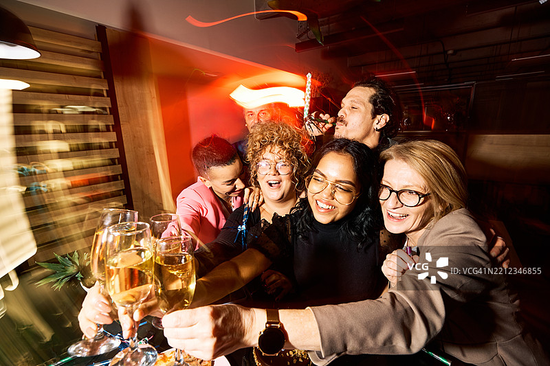 一群跨代朋友在聚会上欢聚一堂，举杯庆祝友谊。图片素材