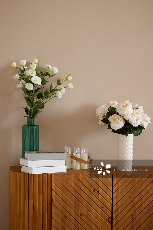 白墙背景上的木质边柜，摆放着郁金香和蜡烛图片素材