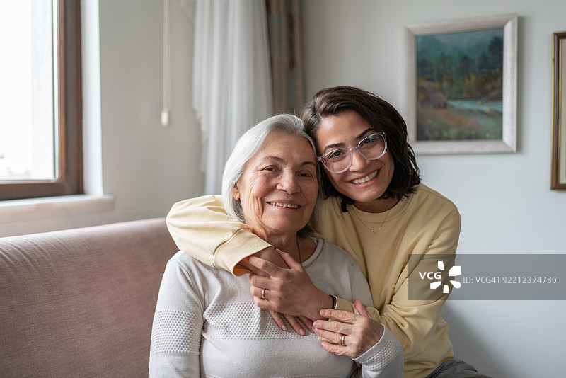 女儿从后面拥抱年长的母亲，握着手。图片素材