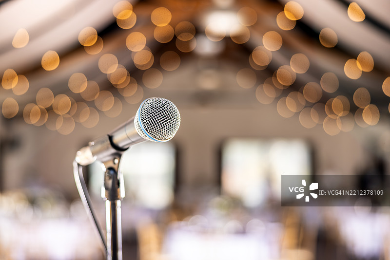 舞台上的公开表演，麦克风在礼堂背景前。图片素材