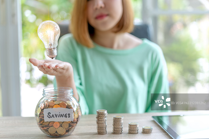 年轻女性手持灯泡，节能理念。图片素材