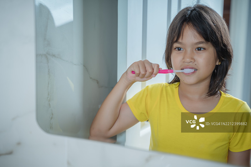 一个小女孩正在镜子前刷牙图片素材