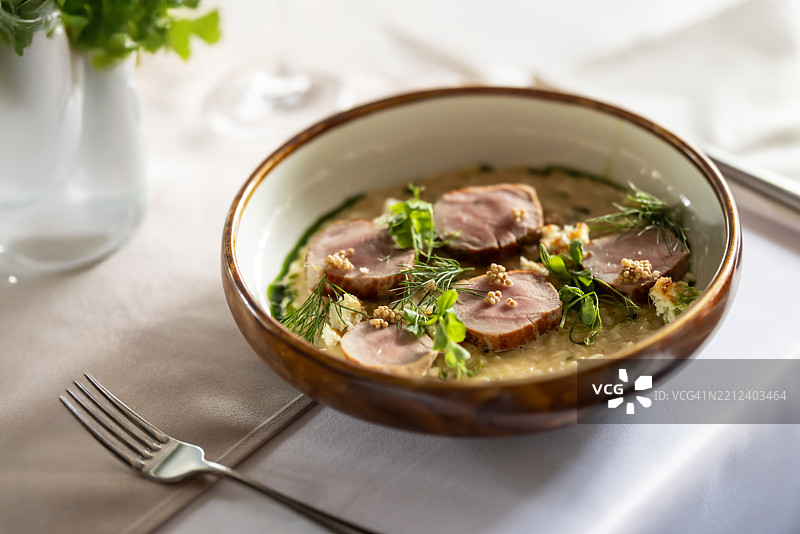 意大利烩饭配猪里脊肉，摆放在餐厅桌上的时尚盘子里。图片素材