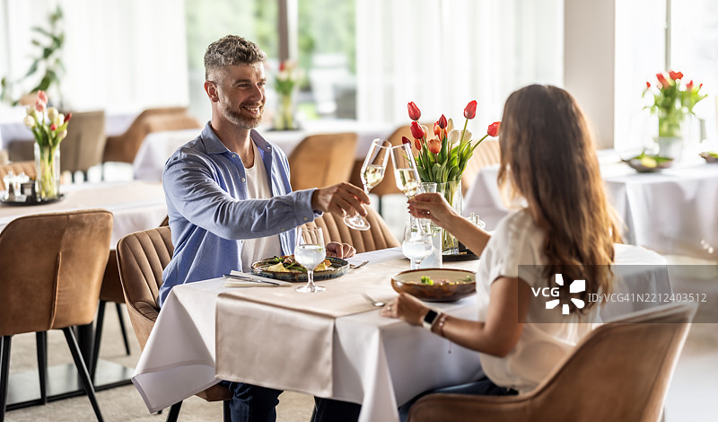 一对恋人正在餐厅享受浪漫晚餐，举杯庆祝香槟或普罗塞克。图片素材