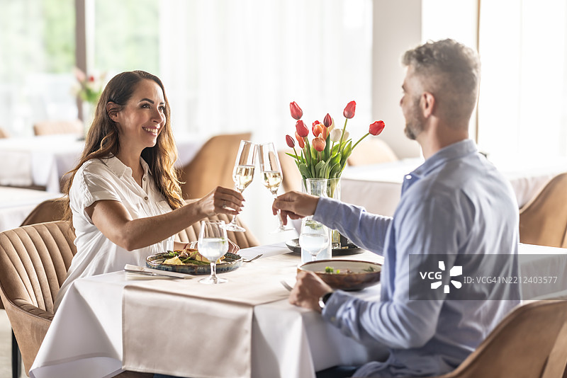 一对恋人正在餐厅享受浪漫晚餐，并举杯庆祝香槟或普罗塞克。图片素材