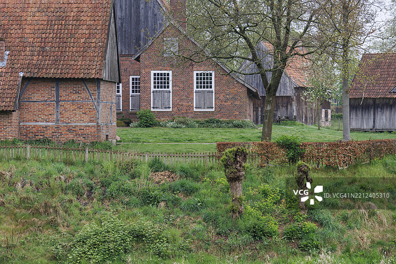 德国明斯特地区弗雷登的乡村环境中，一排历史悠久的半木结构房屋，周围绿意盎然。图片素材