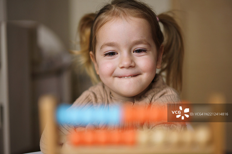 快乐的小女孩在玩算盘玩具图片素材