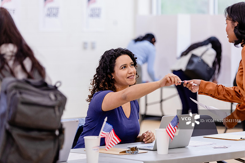 年轻女性在投票站领取笔图片素材