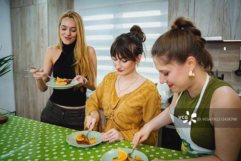 年轻女性在厨房里切橙子蛋糕片图片素材