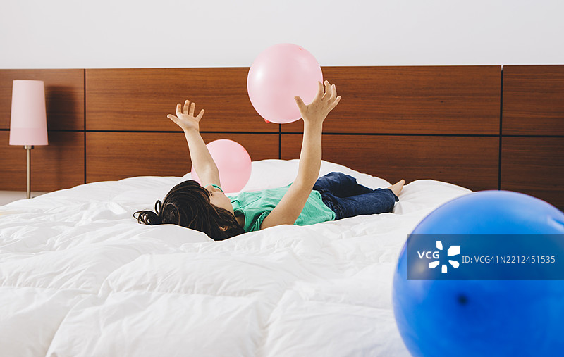孩子在室内床上玩五彩缤纷的气球图片素材