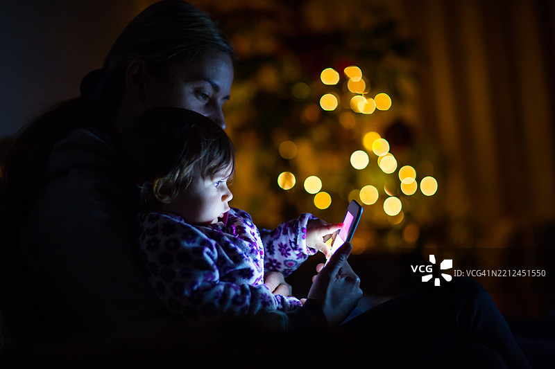 母亲和孩子在夜晚享受安静的手机时光图片素材