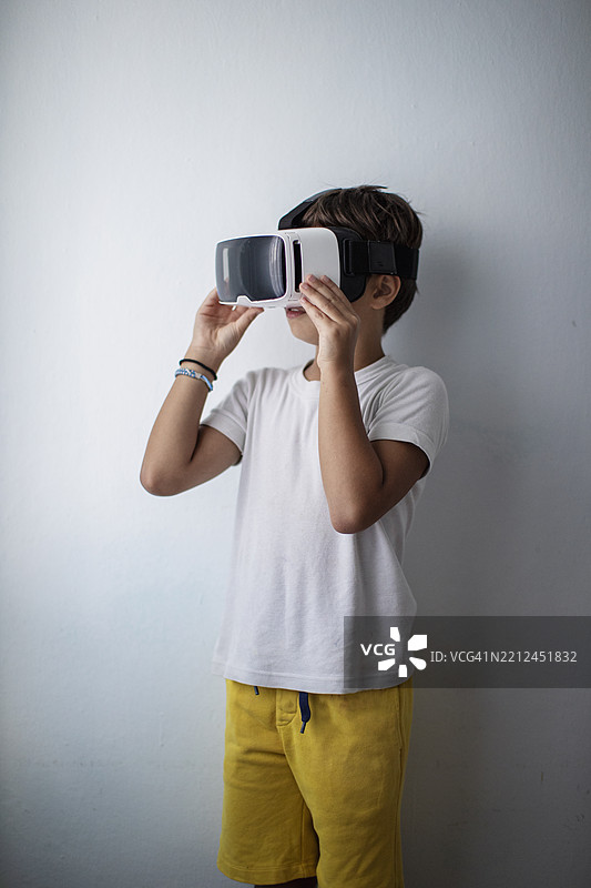 年轻男孩在家中佩戴头戴式显示器探索虚拟现实图片素材