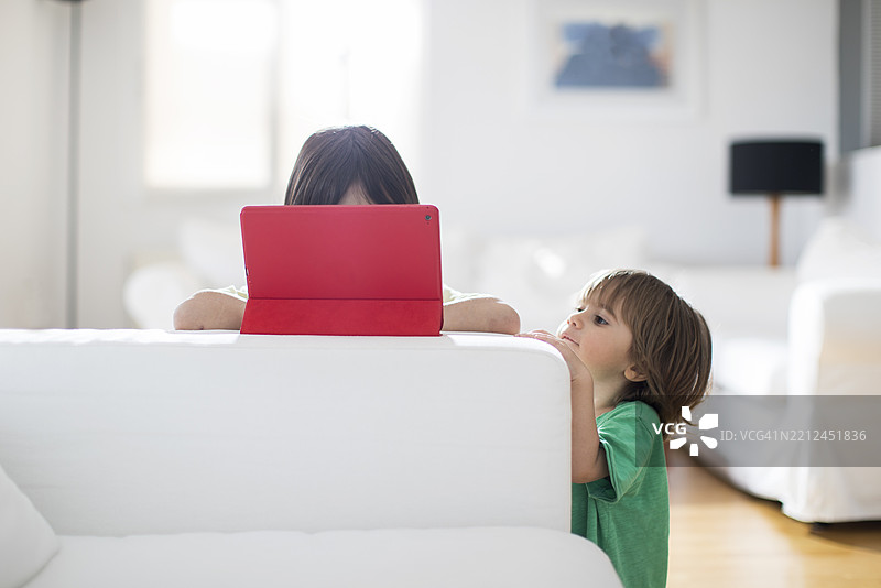 兄弟姐妹在明亮的客厅里一起享受屏幕时间图片素材