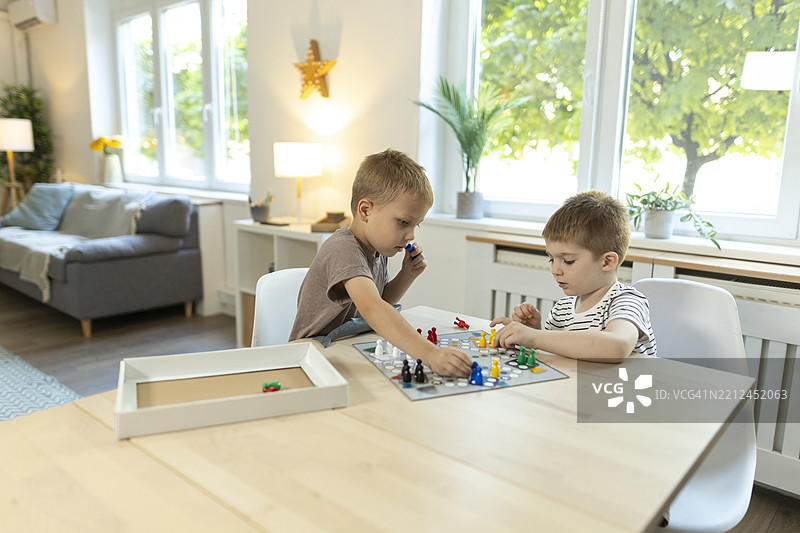 幼儿在厨房桌子上玩飞行棋游戏图片素材