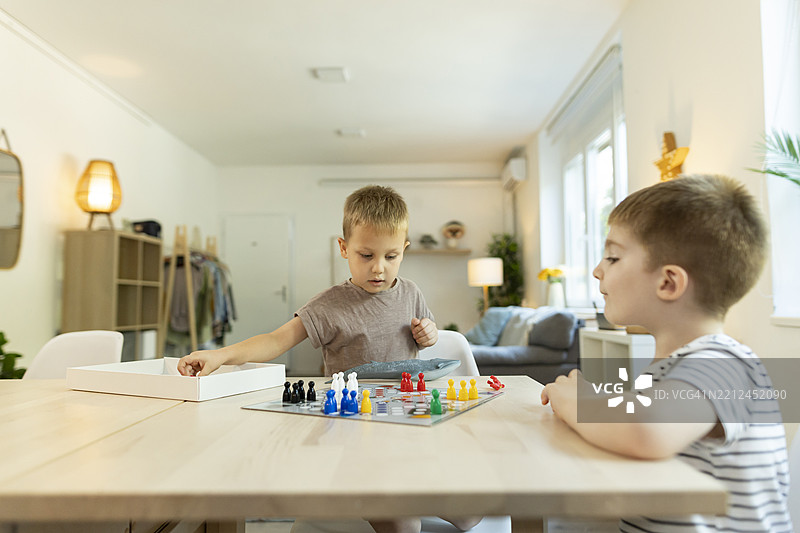 幼儿在厨房桌子上玩飞行棋游戏图片素材