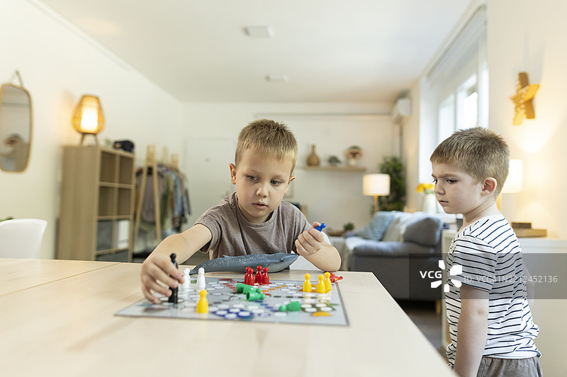 幼儿在厨房桌子上玩飞行棋游戏图片素材