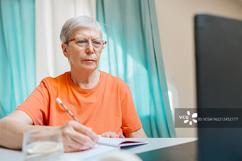 老年女性在笔记本电脑上学习在线课程图片素材