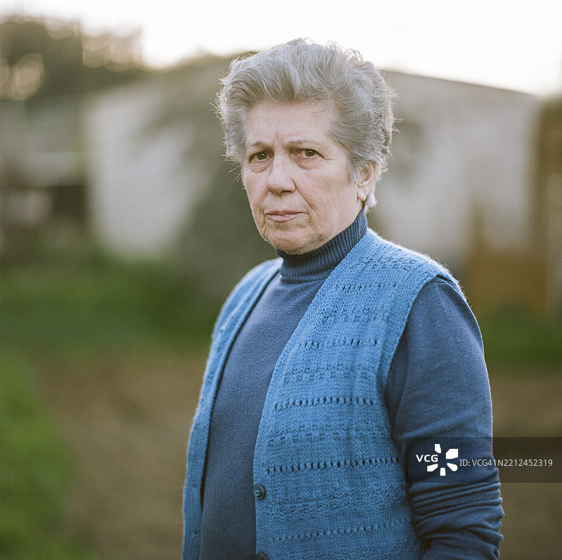 穿着蓝色背心的老年女性在草地户外环境中图片素材