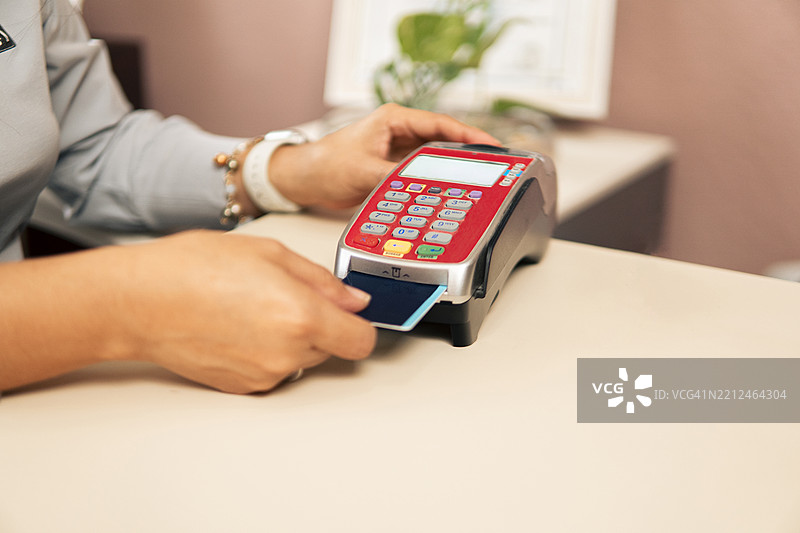 牙科诊所的接待员将信用卡插入POS终端图片素材