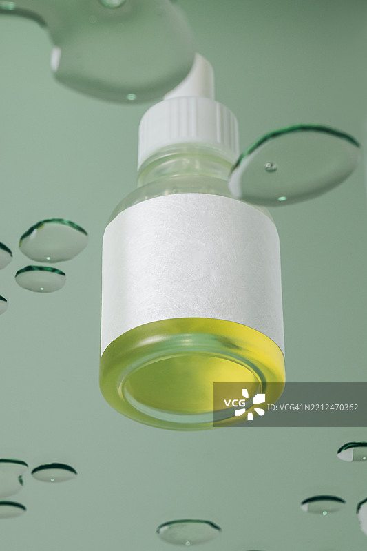绿色背景上带有绿色液体和水滴的玻璃滴管瓶图片素材