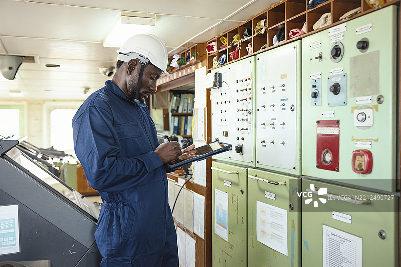 工程师在集装箱货船的桥梁或控制区域使用数字平板电脑。图片素材