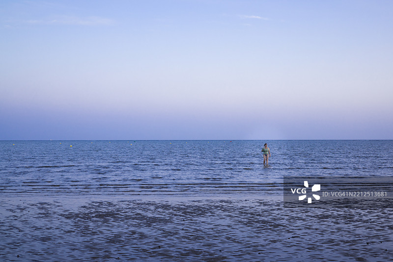 西班牙卡内拉岛海滩的女人在退潮时走在浅水中图片素材