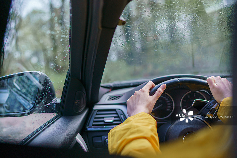 女性的手在雨天驾驶汽车图片素材