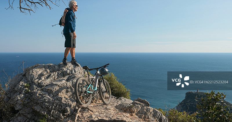的电动自行车骑士坐在海上方的山顶上图片素材