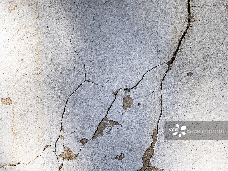 白色水泥墙外的裂缝。图片素材