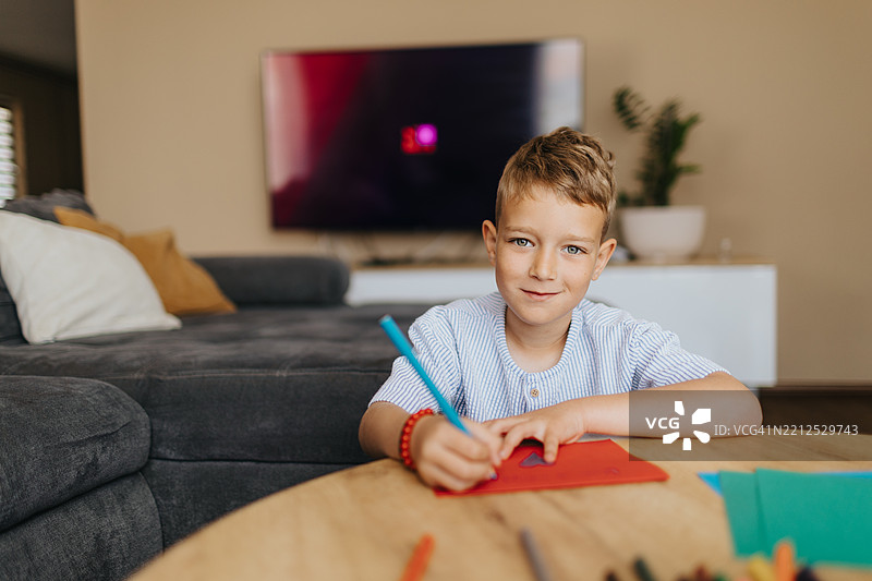 美丽的男学生坐在家中，正在为母亲节写特别的卡片图片素材