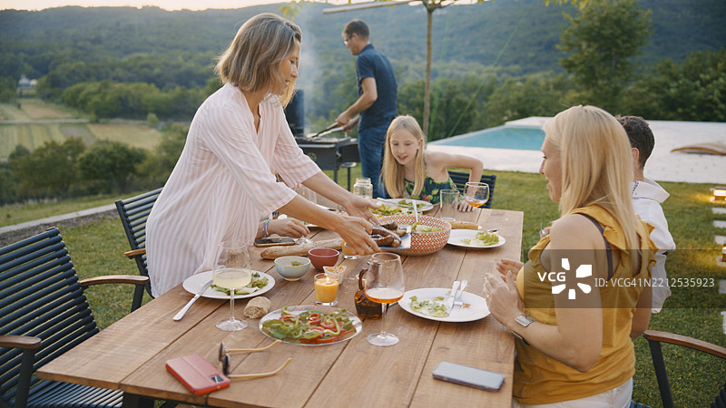 家庭在阳台上享受美丽景观的烧烤晚餐图片素材