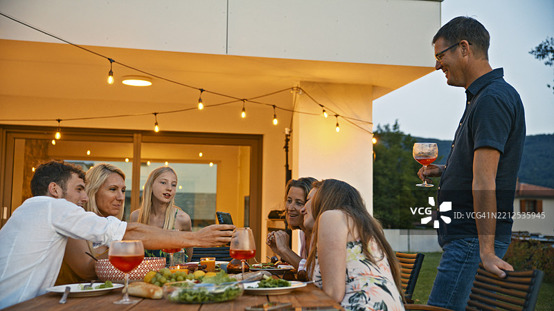 家庭在夏季傍晚的露台上享受晚餐时光图片素材