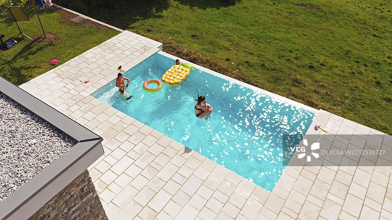 朋友们在夏季假期中跳跃和玩耍于游泳池中图片素材