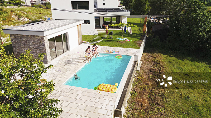 青少年女孩在豪华别墅的游泳池中跳水图片素材