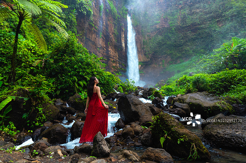 在印度尼西亚东爪哇的卡帕斯比鲁瀑布穿红色裙子的女性肖像图片素材