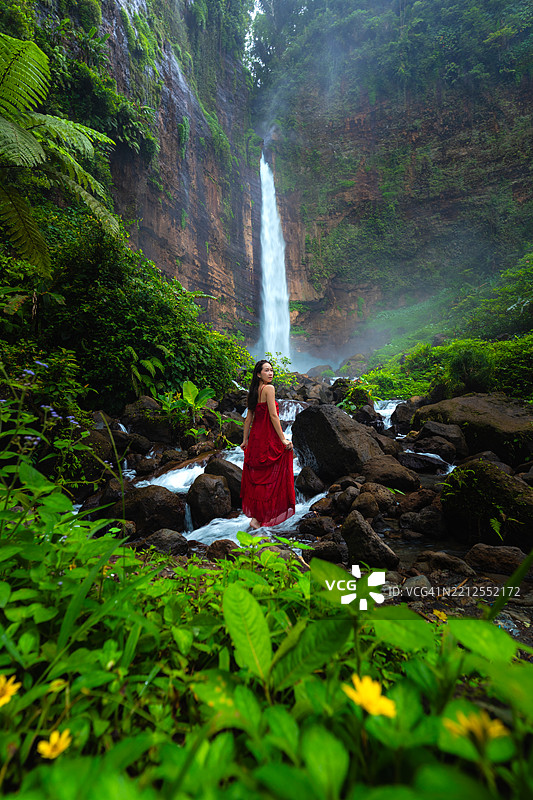 在印度尼西亚东爪哇的卡帕斯比鲁瀑布穿着红色连衣裙的女性肖像图片素材