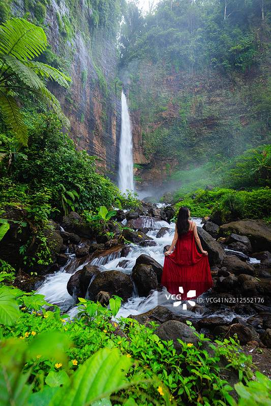 在印度尼西亚东爪哇的卡帕斯比鲁瀑布穿着红色连衣裙的女性肖像图片素材