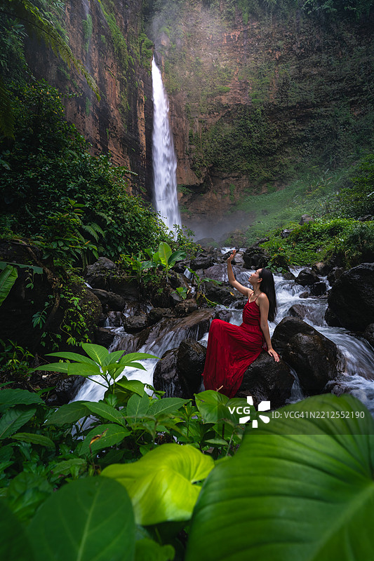 在印度尼西亚东爪哇的卡帕斯比鲁瀑布穿红色裙子的女性肖像图片素材