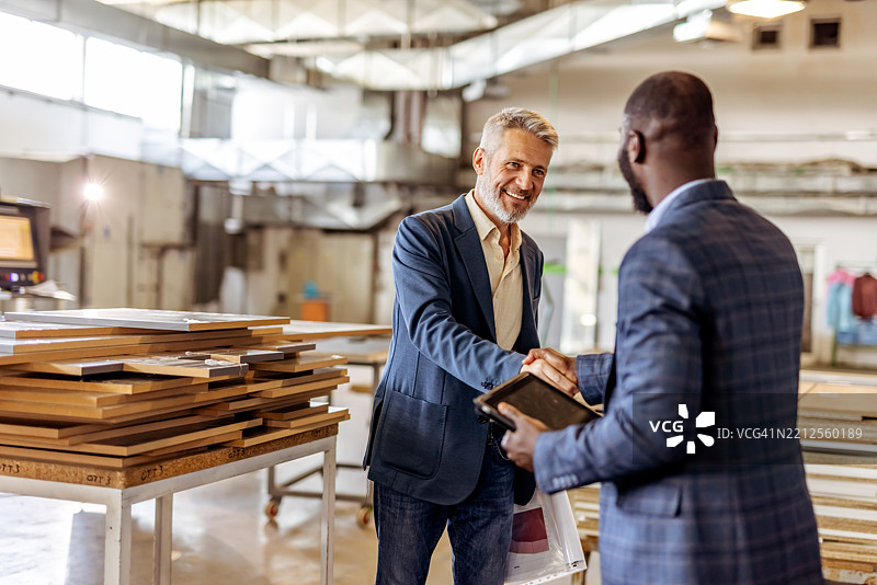 现代工业车间环境中专业人士握手图片素材