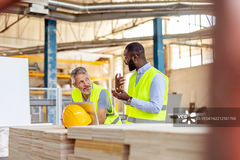 两名建筑工人在工业车间合作，穿着安全背心图片素材