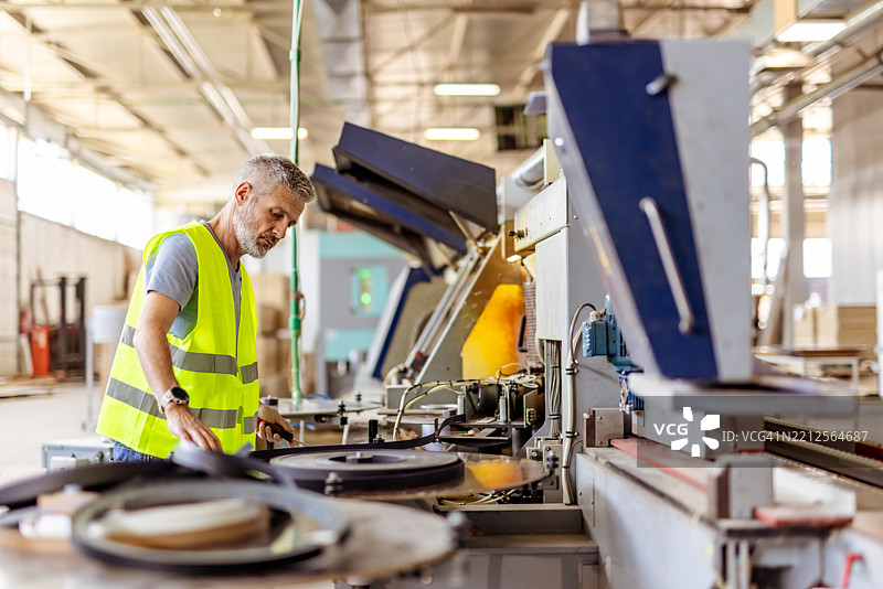 仓库环境中操作机器的工业工人图片素材
