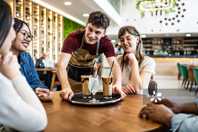 年轻的服务员在咖啡馆为顾客提供饮品图片素材