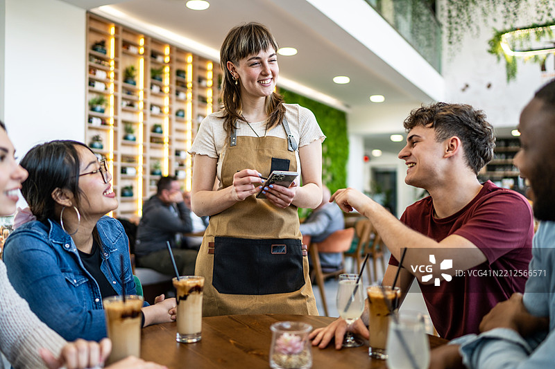 年轻女服务员在现代咖啡馆为顾客点单图片素材