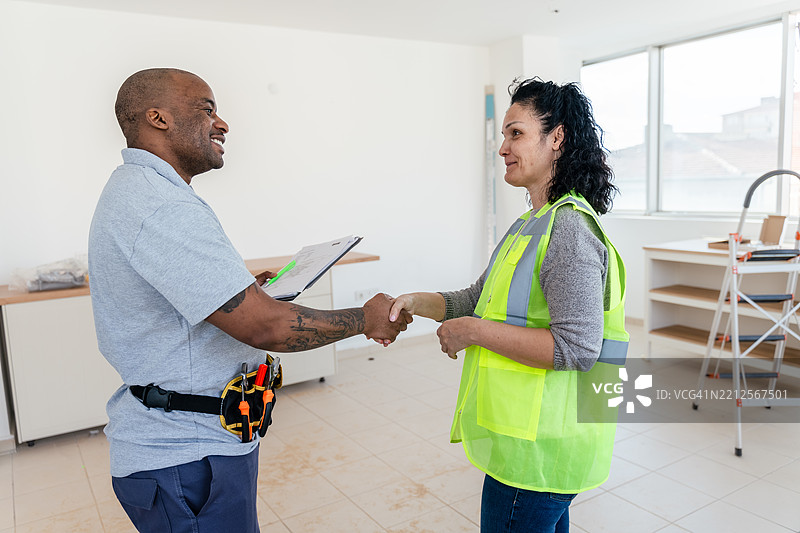建筑工人在新厨房内审查翻新计划图片素材